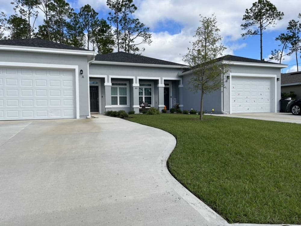 Modern gray single-story home with white garage doors and columned front entrance