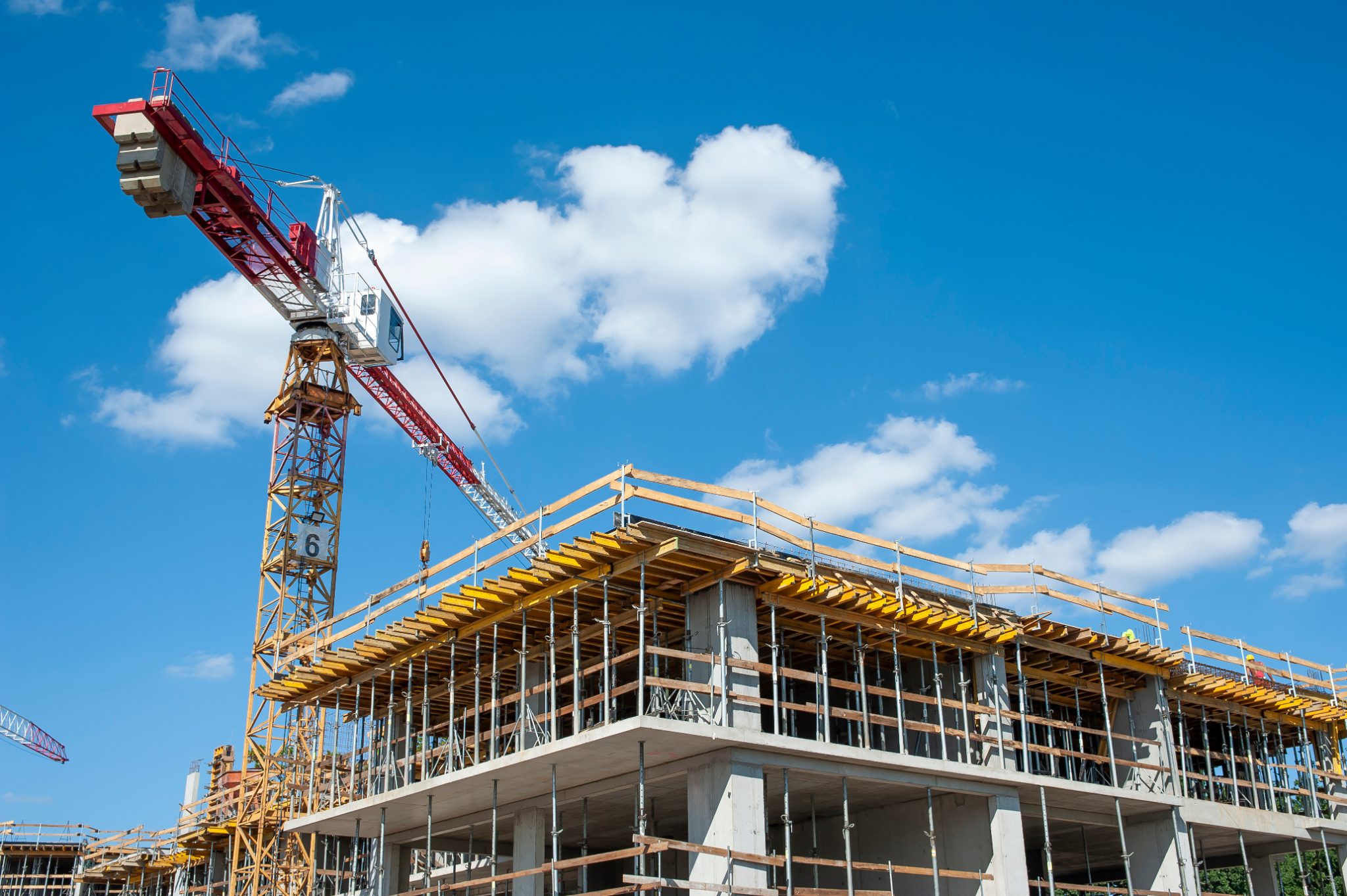 Construction site with tower crane lifting materials over multi-story concrete building frame